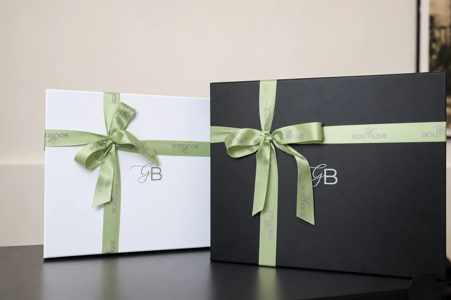 Cajas blancas y negras de Gift Boutique decoradas con cintas verdes de la marca
