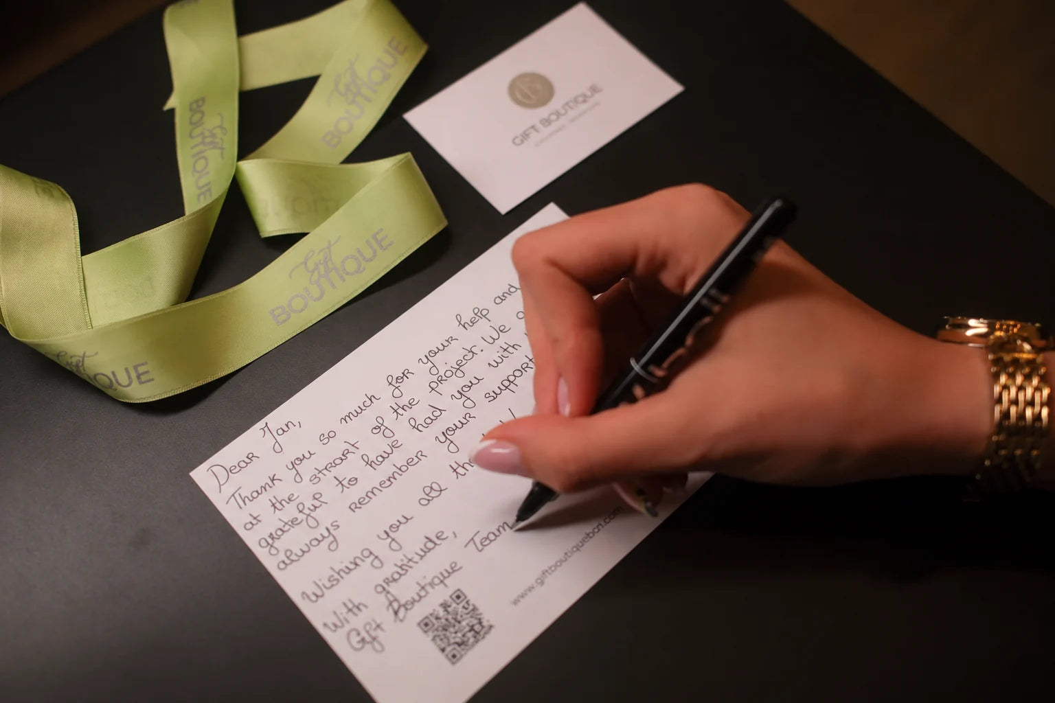 Una tarjeta de Gift Boutique escrita a mano junto a una cinta verde de la marca
